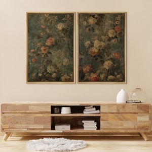 May include: Two framed vintage floral prints with a faded, antique aesthetic. The prints feature a delicate arrangement of pink and white flowers on a dark blue background.