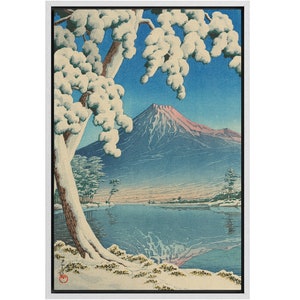 Puede incluir: Una estampa en madera que representa el monte Fuji en la distancia, cubierto de nieve. Un gran &aacute;rbol con ramas cubiertas de nieve se encuentra en primer plano, con un lago en el plano intermedio. La estampa est&aacute; enmarcada en un marco blanco.