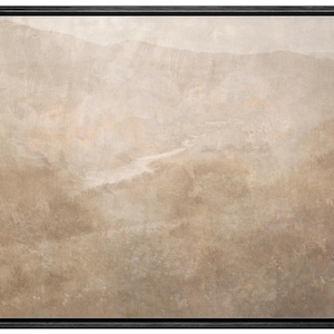 May include: A framed landscape art print featuring a muted color palette of beige, tan, and brown. The artwork depicts a mountainous terrain with a river winding through the valley. The black frame adds a modern touch.