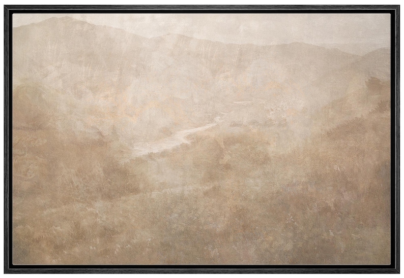 May include: A framed landscape art print featuring a muted color palette of beige, tan, and brown. The artwork depicts a mountainous terrain with a river winding through the valley. The black frame adds a modern touch.