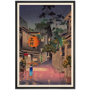 May include: A Japanese woodblock print depicting a rainy night scene in a narrow street lined with traditional buildings. A woman with an umbrella walks in the street, and a lantern with the Japanese characters "吉井" hangs above a shop.