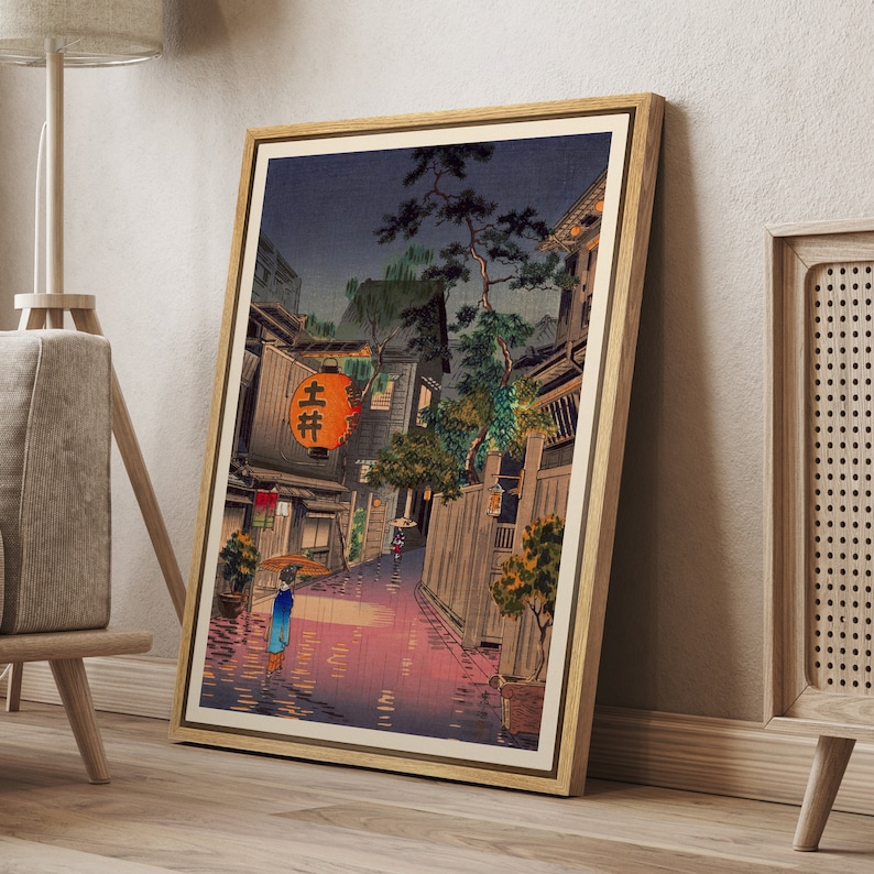 May include: A vintage Japanese woodblock print depicting a rainy night scene in a narrow street lined with traditional buildings. A woman with an umbrella walks in the rain, and a red lantern with the Japanese characters "上井" hangs above a shop entrance.