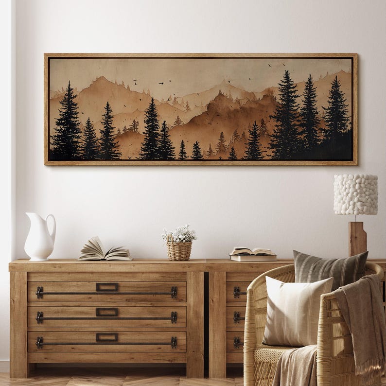 May include: A framed landscape art print featuring a sepia-toned mountain scene with silhouetted pine trees. The artwork has a rustic, natural aesthetic, perfect for home decor. The frame is a warm brown color.
