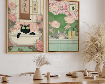 May include: Two framed art prints with a Japanese aesthetic. One features a black cat in a bathtub, the other a gray cat relaxing. Both have floral and botanical elements, with Japanese text and a soft color palette.