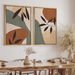 May include: Two framed abstract art prints with a green, brown, and beige color scheme. The prints feature stylized leaves and organic shapes.