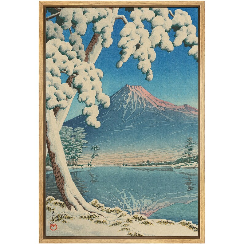 Puede incluir: Una estampa en madera que representa el monte Fuji en la distancia, con un &aacute;rbol nevado en primer plano y un lago que refleja la monta&ntilde;a. La estampa est&aacute; enmarcada en un marco de madera.