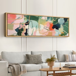 May include: Abstract art print in a wooden frame with pink, green, blue, and orange colors. The print features abstract shapes and lines.