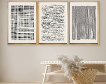 Peut inclure: Trois impressions d'art abstrait en noir et blanc encadrées avec des motifs géométriques. Les impressions sont accrochées à un mur beige clair au-dessus d'un banc blanc avec un panier tissé et une plante de pampa sèche.