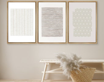 Peut inclure: Trois impressions d'art abstrait encadrées avec des motifs géométriques dans des tons beige et blanc. Les impressions sont accrochées à un mur beige clair au-dessus d'un banc en bois blanc avec un panier tissé.