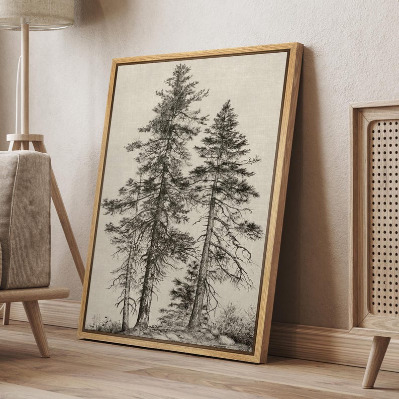 May include: A framed canvas print featuring a detailed black and white illustration of several tall pine trees. The artwork has a neutral color palette and is displayed in a natural wood frame, leaning against a wall.