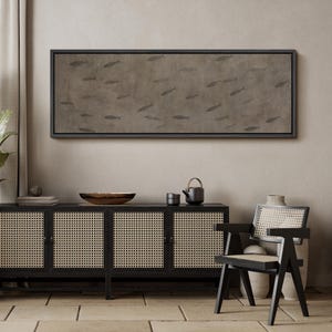 Puede incluir: Una obra de arte rectangular enmarcada que representa peces sobre un fondo marr&oacute;n. La obra de arte est&aacute; encima de un mueble negro con puertas de ca&ntilde;a tejida. Tambi&eacute;n se ve una silla negra con respaldo de ca&ntilde;a tejida y un jarr&oacute;n decorativo.
