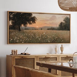 Puede incluir: Un cuadro rectangular de paisaje que muestra una puesta de sol sobre un campo de margaritas blancas y un &aacute;rbol grande. La escena incluye colinas suaves en la distancia bajo un cielo naranja suave, con peque&ntilde;os puntos de luz en la pradera.
