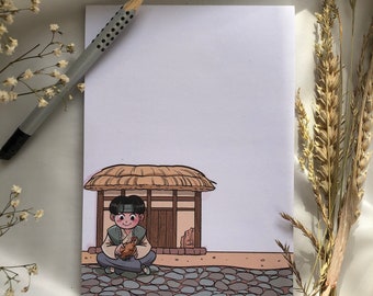 May include: A cartoon illustration of a person sitting on a stone path in front of a small house with a thatched roof. The person is holding a small brown bird in their hands. The house has a wooden door and windows.
