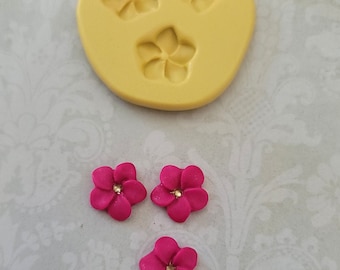 May include: Three pink flower-shaped silicone molds with a yellow silicone mold showing three flower shapes.