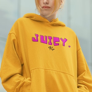 May include: A yellow hoodie with a pink "Juicy 94" graphic print.