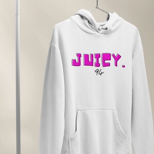 May include: White hoodie with a pink "JUICY." logo and "94" written underneath.
