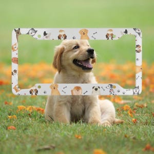 May include: A rectangular number plate frame featuring a white background decorated with a repeating pattern of various dog breeds, small paw prints, and bone icons. The frame has four mounting holes, one in each corner, for vehicle attachment.
