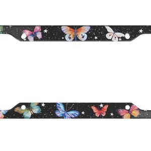 May include: Black license plate frame with a colorful butterfly design on a black background with white stars.