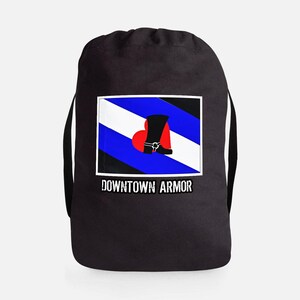 May include: Black drawstring bag with a rectangular graphic. The graphic features a stylized flag with blue and white stripes, a black boot, and a red heart. The text "DOWNTOWN ARMOR" is printed below the graphic.