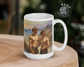 May include: White ceramic mug featuring a vintage-style painting of two shirtless men on a beach. The artwork depicts the men standing near the ocean with a coastal landscape in the background. The mug has a curved handle and a Home Jungle Treasures logo.