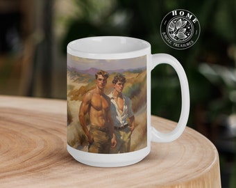 May include: White ceramic mug with a colorful image of two men standing in a landscape. The image shows a sandy beach with green hills in the background. The men are wearing casual clothing and have short hair. The mug has a black handle and the words "Jungle Treasures" are printed on the side.