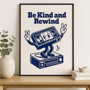 May include: A blue and white print of a vintage VHS tape with legs and arms, giving a peace sign with each hand. The tape is standing on top of a vintage VCR. The text "Be Kind and Rewind" is printed above the tape.