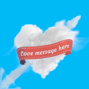 Puede incluir: Una nube blanca con forma de coraz&oacute;n con una cinta roja que dice "Love message here" sobre un cielo azul.