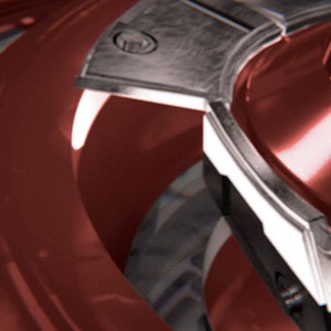 Può includere: Primo piano di un oggetto metallico rosso e argento con un design circolare. L'oggetto ha una superficie lucida e riflettente e sembra far parte di una macchina o dispositivo più grande.