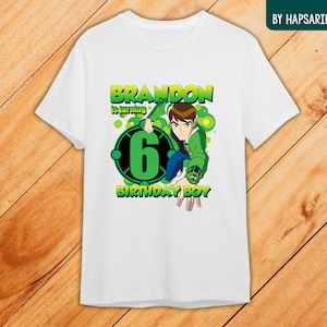 May include: White t-shirt with a green cartoon character, a green and black circle with the number 6, and the text "Brandon is turning 6 Birthday Boy".