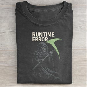 Op de afbeelding: Donkergrijs t-shirt met de tekst "RUNTIME ERROR" boven een illustratie van een zeisdrager met een groene zeis. De zeisdrager draagt een capuchon.