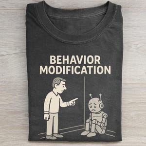 Könnte beinhalten: Dunkelgraues T-Shirt mit dem weißen Schriftzug "BEHAVIOR MODIFICATION". Die Grafik zeigt eine Person, die auf einen traurigen Roboter zeigt. Der Roboter sitzt in einer Ecke, und die Person steht.