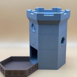 Op de afbeelding: Een blauwe dobbelsteentoren met een textuur die op een kasteel lijkt. De toren heeft een zeshoekige basis en een bijpassende bruine bak. De bak heeft een decoratief patroon. De toren heeft zeshoekige ramen.