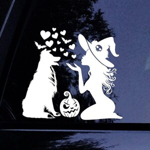 May include: A white silhouette of a witch wearing a hat with a skull design blowing a kiss to a dog. The witch is kneeling and the dog is standing. There are hearts and bats in the background. A jack-o-lantern is between the witch and the dog.