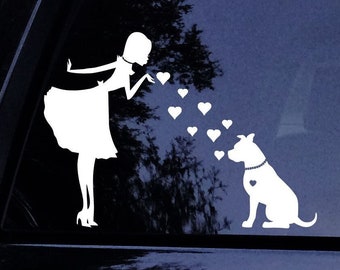 Puede incluir: Una silueta blanca de una mujer soplando corazones hacia una silueta blanca de un perro. La mujer lleva un vestido y el perro lleva un collar con un dije de corazón.