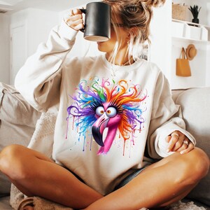 May include: A white sweatshirt with a colorful graphic of a flamingo with a crazy hairdo. The flamingo is pink with colorful paint splatters around it.