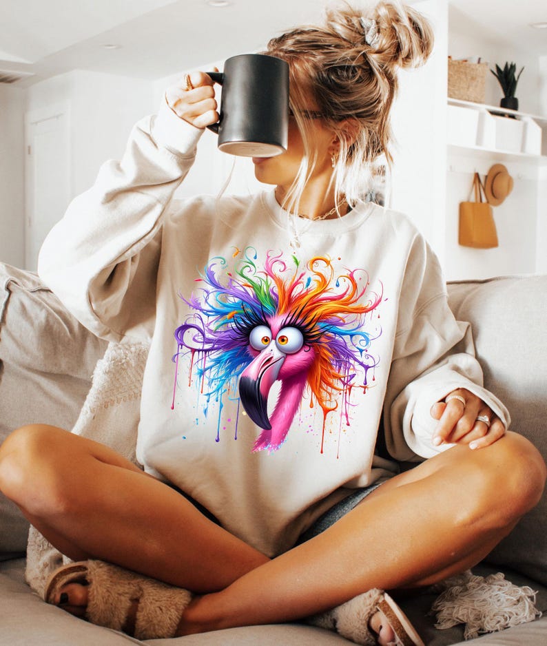 May include: A white sweatshirt with a colorful graphic of a flamingo with a crazy hairdo. The flamingo is pink with colorful paint splatters around it.