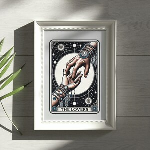 Pu&ograve; includere: Una carta dei tarocchi con un'illustrazione in bianco e nero di due mani che si raggiungono a vicenda. La carta &egrave; incorniciata in una cornice bianca e ha il testo "THE LOVERS" in basso.