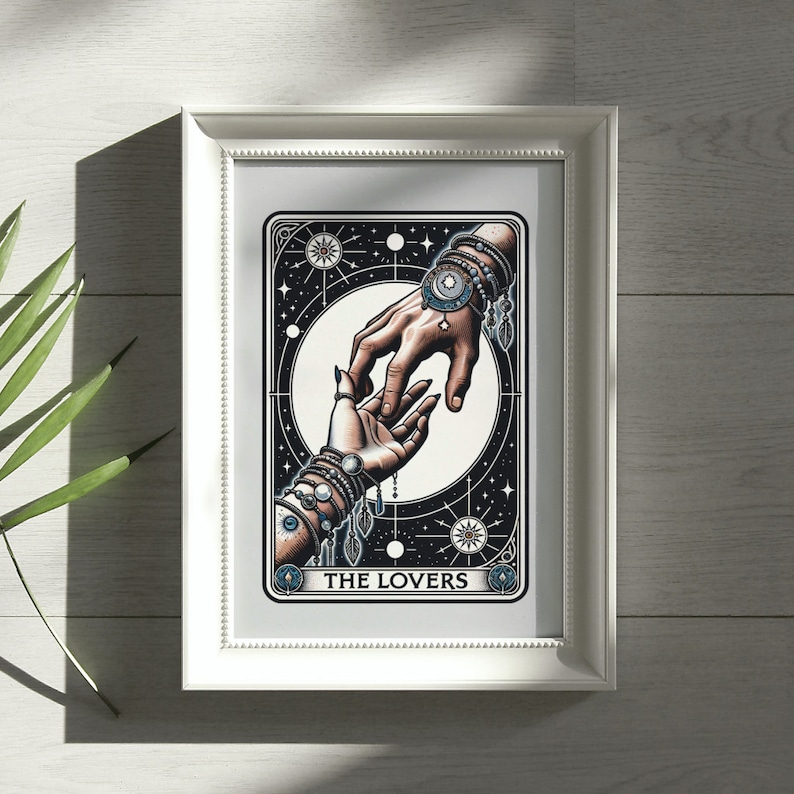 Pu&ograve; includere: Una carta dei tarocchi con un'illustrazione in bianco e nero di due mani che si raggiungono a vicenda. La carta &egrave; incorniciata in una cornice bianca e ha il testo "THE LOVERS" in basso.