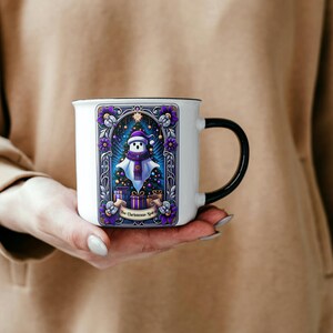 May include: White ceramic mug with a black handle. The mug features a colorful illustration of a snowman with a purple scarf and a Christmas tree with presents. The text "The Christmas Spirit" is printed on the mug.