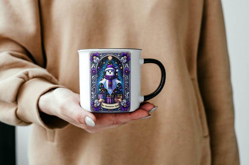 May include: White ceramic mug with a black handle. The mug features a colorful illustration of a snowman with a purple scarf and a Christmas tree with presents. The text "The Christmas Spirit" is printed on the mug.