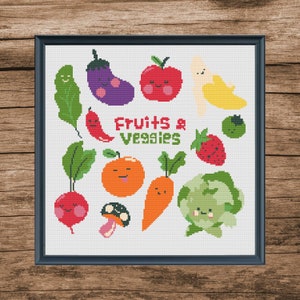 May include: A framed cross-stitch featuring cartoon fruits and vegetables. The design includes a red apple, purple eggplant, orange carrot, and a yellow banana. The text "Fruits & Veggies" is in the center of the design.