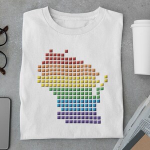 May include: A white t-shirt featuring a rainbow pixelated outline of the state of Wisconsin.
