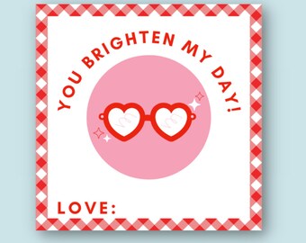 May include: A white card with a red and white checkered border. The card has a pink circle with red heart-shaped sunglasses and the text "YOU BRIGHTEN MY DAY!" in red. The card also has the text "LOVE:" in red.