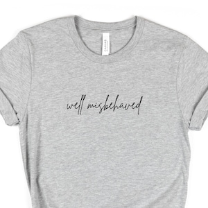 Peut inclure: T-shirt gris avec le texte "well misbehaved" en écriture noire.
