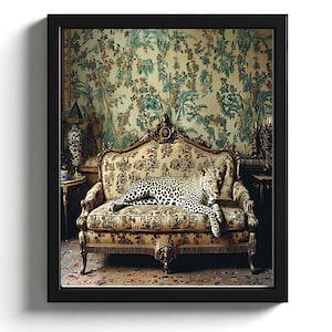 Op de afbeelding: Een ingelijste kunstdruk met een luipaard dat rust op een bloemig patroonbank. De bank heeft gouden details en staat tegen een achtergrond van vintage bloemenbehang. Het kunstwerk is ingelijst in een zwarte lijst.