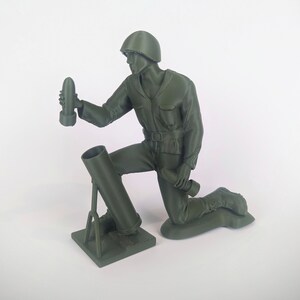 Peut inclure: Une figurine de soldat en plastique vert agenouill&eacute; tenant un obus de mortier. Le soldat porte un casque et a un fusil en bandouli&egrave;re. Le mortier est mont&eacute; sur un tr&eacute;pied.