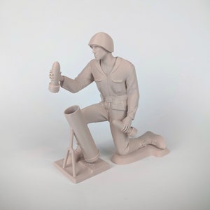 Peut inclure: Une figurine en plastique beige d'un soldat agenouill&eacute; et chargeant un mortier. Le soldat porte un casque et tient un obus de mortier dans sa main droite. Le mortier est sur un tr&eacute;pied et a un canon point&eacute; vers le haut.