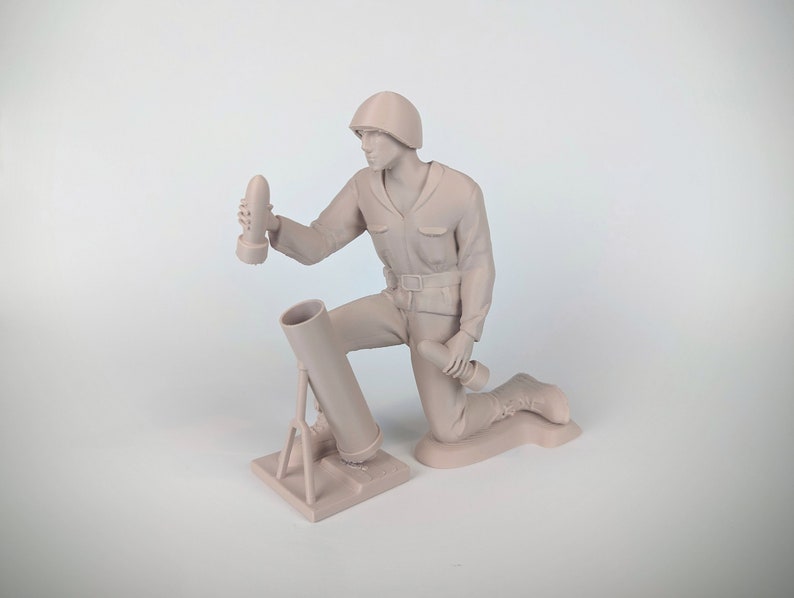 Peut inclure: Une figurine en plastique beige d'un soldat agenouill&eacute; et chargeant un mortier. Le soldat porte un casque et tient un obus de mortier dans sa main droite. Le mortier est sur un tr&eacute;pied et a un canon point&eacute; vers le haut.