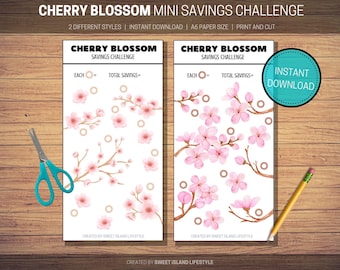 May include: Two white Cherry Blossom Mini Savings Challenge printables with pink floral designs. The text reads "Cherry Blossom Savings Challenge" and "Instant Download". A pair of teal scissors and a yellow pencil are also visible.