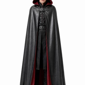 May include: A floor-length black hooded cloak with a deep red interior lining. The garment features a front closure with two dark metal buckles and a series of vertical buttons down the center, worn over a matching black long-sleeved tunic and pants.